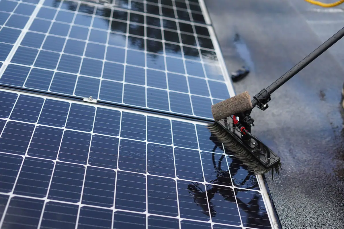 Close-up of solar panels being cleaned with a brush