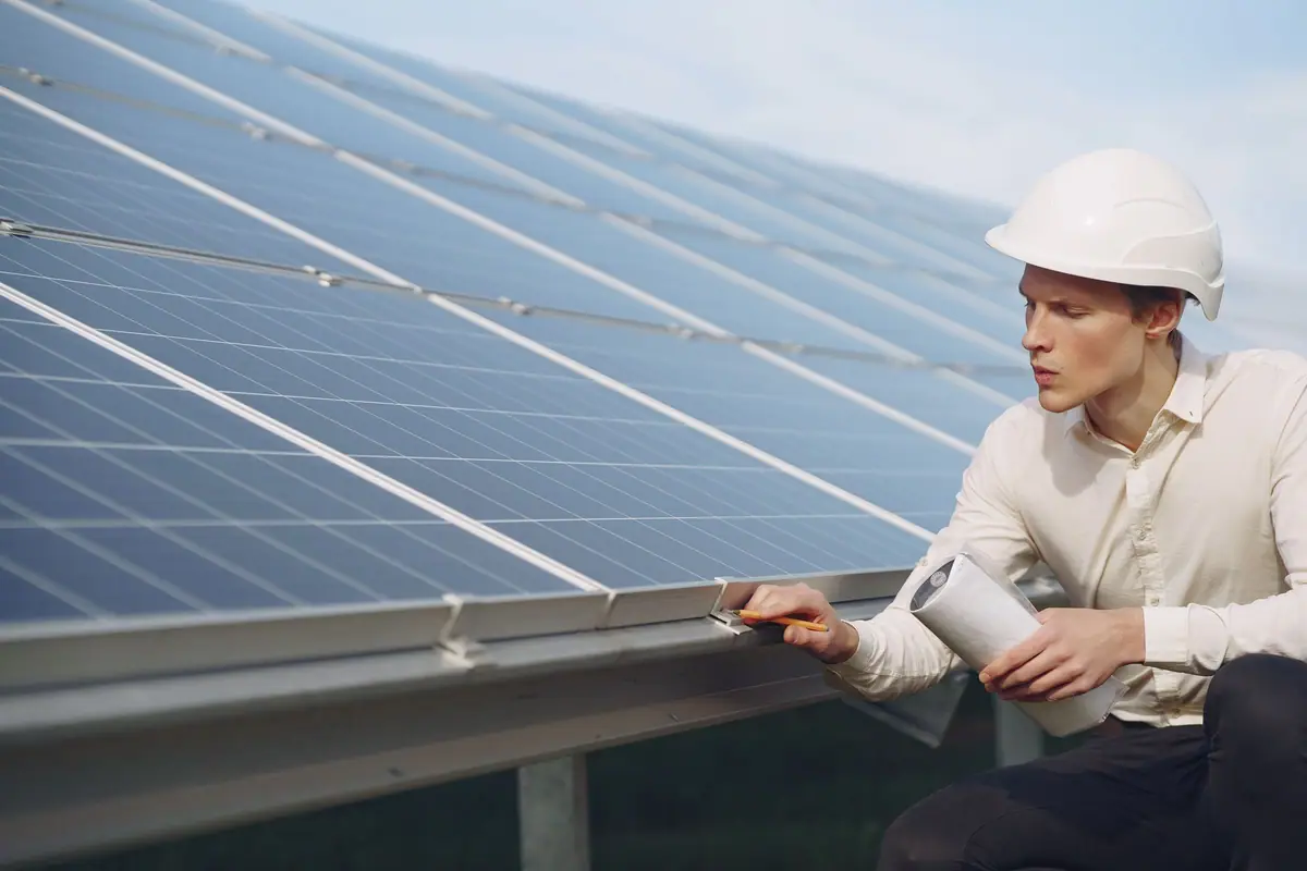 Engineer in a hard hat inspecting solar panels