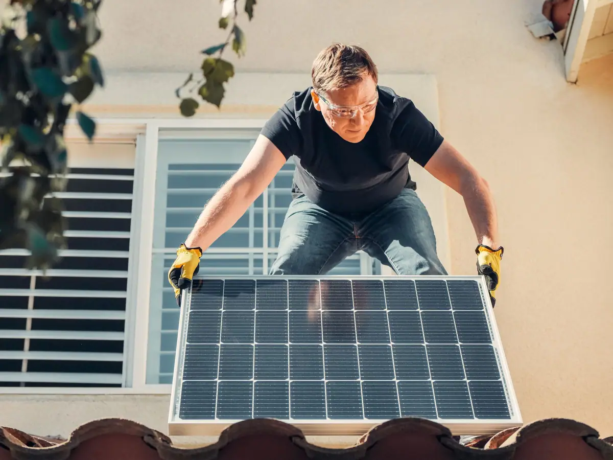 Installer in safety glasses fitting a solar panel