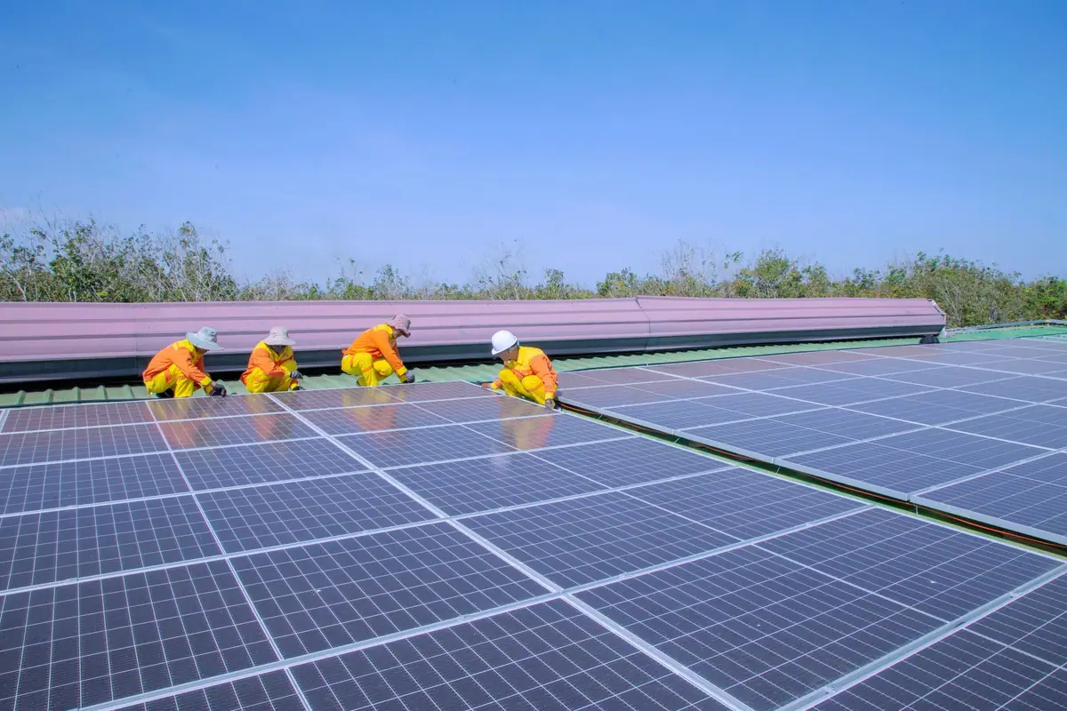 Installation team fitting solar panels on a large roof