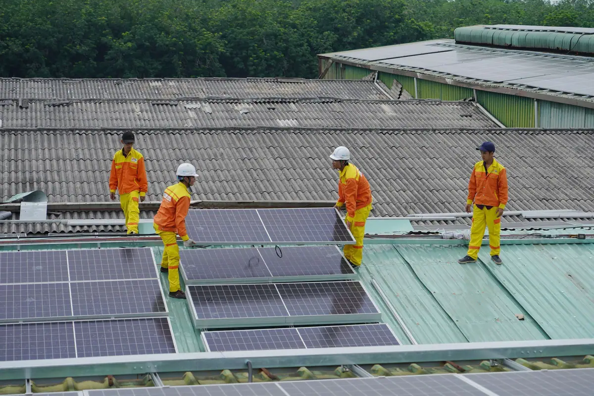 Workers in safety gear installing rooftop solar panels