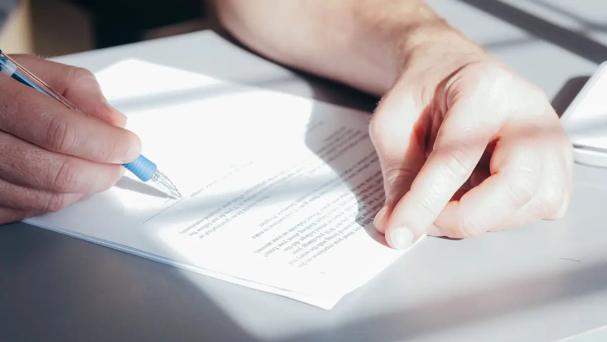 Signing paperwork with a blue pen